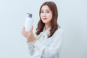 白色のシャンプーを持ったカメラ目線の女性