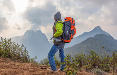 Hiker standing relaxing on top mountain sunset background. Hiker men's hiking living healthy active lifestyle.