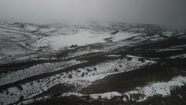 Drone view of mountain pass with snowy hills and low clouds on dark winter day near Gunnison Colorado