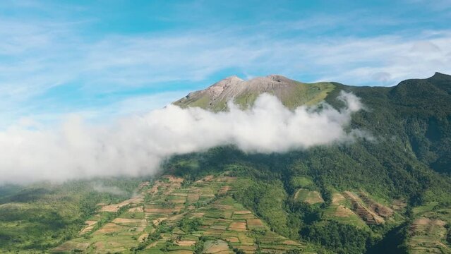 Aerial drone of farmland with plantings against a background of mountains and blue sky. Canlaon volcano. Negros, Philippines