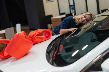 Fototapeta na wymiar Happy caucasian woman hugging a new car. Car as a gift.
