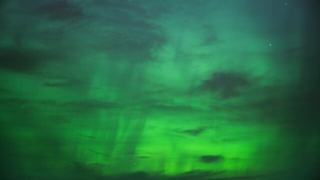 The night sky lit with bright green color of Northern Lights (Aurora Borealis). Timelapse. 