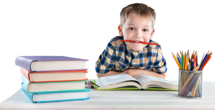 Happy school child with school supplies, sitting at a desk learning in class