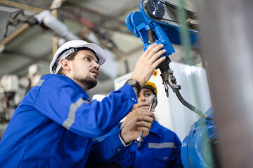Robotic technicians tighten and loosen components with screwdriver and plier to perform safety maintenance. Measuring current, voltage, resistance, capacity, temperature with digital clamp meter.