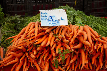 Pile of orange carrots at farmers market with price sign handwritten