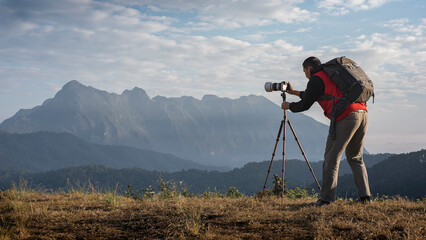 Adventure photographer is standing and taking pictures of the mountain landscape.