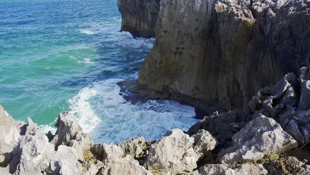Breathtaking view of rough rocky cliff near calm sea on Ribadesella coast under gray sky in Asturias