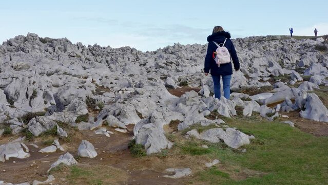 Woman strolling among strange rock formations on the coast of northern Spain, Asturias.