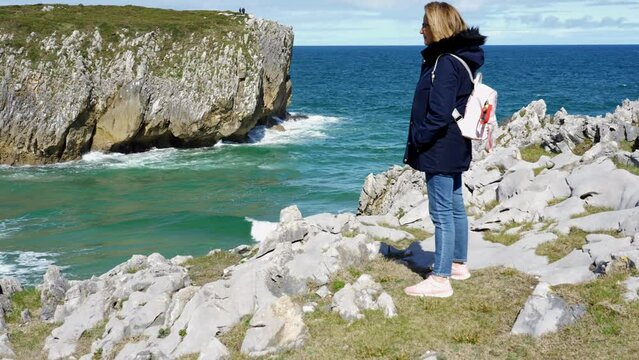 Woman enjoying the seascape of great beauty with cliffs and high mountains in Asturias, Spain.