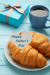 Father's day concept with gift, card and breakfast. Breakfast for dad with croissant and coffee.