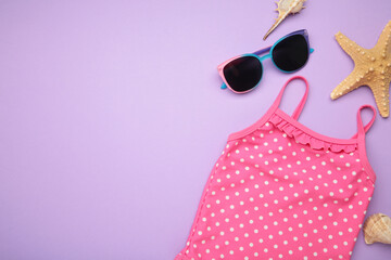 Summer kid's vacation concept - swimsuit with cute sunglasses on purple background. Holiday concept, fashion child