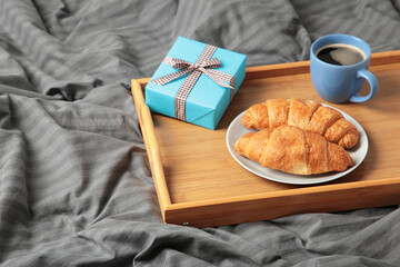 Father's day concept with gift and breakfast on tray. Breakfast for dad with croissant and coffee.