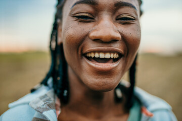 Portrait outdoors of a beautiful young afro american woman smiling at sunset. Lifestyle