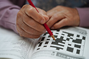 Asian elderly woman playing sudoku puzzle game to practice brain training for dementia prevention,...