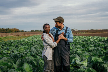Portrait of a multiracial working couple spending time on their cabbage agricultural land.