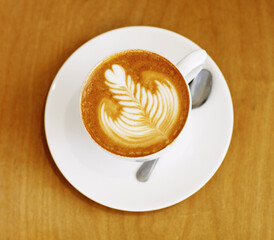 Latte art, coffee and top view of drink on table in cafe, closeup of hot beverage and artistic design with milk foam. Cappuccino, espresso and creative pattern on caffeine liquid brew in a cup