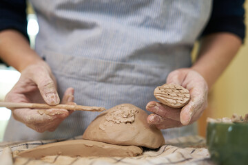 woman forming clay pot shape by hands, closeup in artistic studio