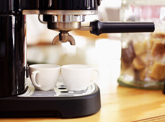 Coffee, cups and machine on table in cafe for cappuccino, latte or hot drink. Restaurant, electrical appliance and caffeine mug for making or brewing espresso in retail shop or small business.