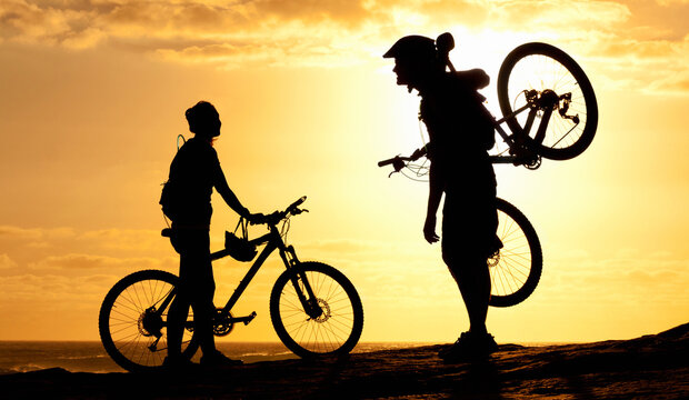 Sunset, silhouette and couple with bike at beach for relax, fitness and summer break. Travel, vacation and training with man and woman with bicycle on coastline for cycling, bonding and wellness