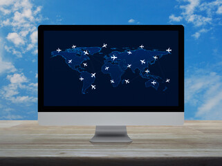 Flight routes airplanes connection and world map on computer screen on wooden table over blue sky,...