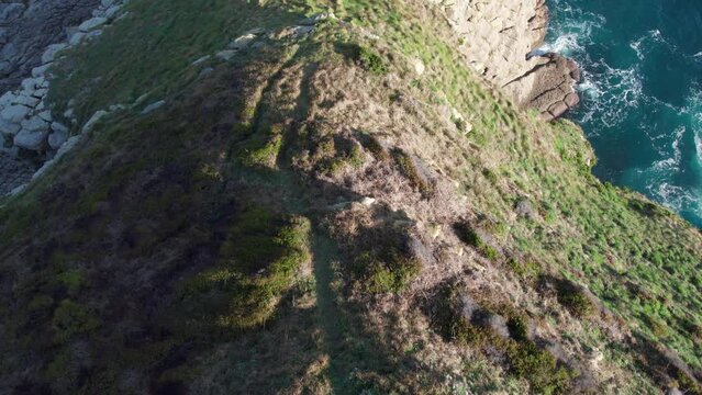 Epic green grass highland tilt up to sunny sea ocean horizon droneshot aerial, shot on spanish outdoor nature in Spain, playa de Tagle.
