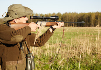 Hunting, rifle and target with a ranger man aiming a weapon on a field outdoor in nature for sport. Gun, scope and shooting with a male game hunter holding a sniper outside in a grass environment
