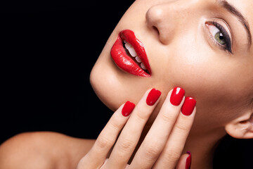 Fototapeta premium Beauty, makeup and woman with red lipstick and nails in a studio with a self care pamper treatment. Cosmetic, portrait and half face closeup of female model with a facial routine by black background.