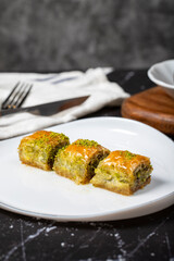 Baklava with pistachio on a dark background. Traditional Turkish baklava. Local name ankara sarmasi. Close up