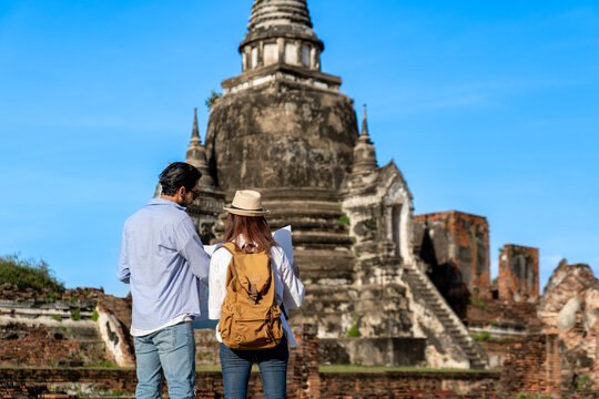 young couple tourist using paper map guide while traveling to Wat Phra Si Sanphet in Ayutthaya historical park Pagoda ancient temple, UNESCO attractive famous place during honeymoon holiday vacation