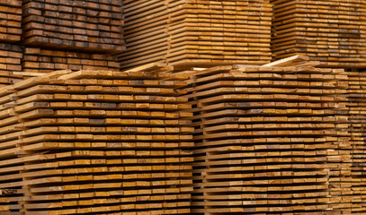 Wooden boards, lumber, industrial wood, timber. Pine wood timber stack of natural rough wooden boards on building site. Industrial timber building materials