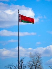 The national flag of the Republic of Belarus on a large flagpole against a blue sky.
