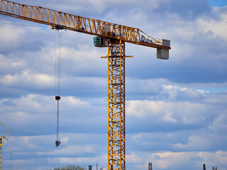 Construction cranes on a construction site against the blue sky