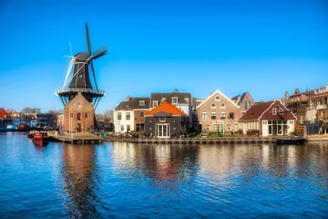 Foto op Canvas The Binnen Spaarne Canal Running through Haarlem, the Netherlands, with the Famous Windmill De Adriaan © Rolf