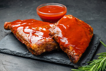 Pork ribs in barbecue sauce with rosemary on a dark background.