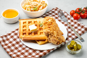 Crispy fried chicken and waffles, a traditional American dish served with syrup and coe slaw.