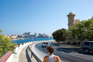 Female jogger way down at Malta island opposite of City of Valletta on a sunny summer day. Photo...