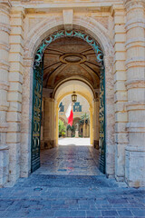 Arch at entrance of Grandmaster's Palace with with maltesian flag in the background r on a sunny hot summer day. Photo taken August 9th, 2017, Valletta, Malta.