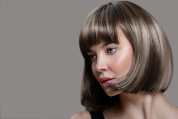 Portrait of beautiful fashion woman with bob hairstyle. Thick short wig. Gray background