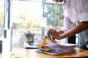 Businesswoman hands working on stacks of paper documents to search and review documents piled on...