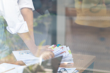 Businesswoman hands working on stacks of paper documents to search and review documents piled on table before sending them to board of directors to use  correct documents in meeting with Businessman