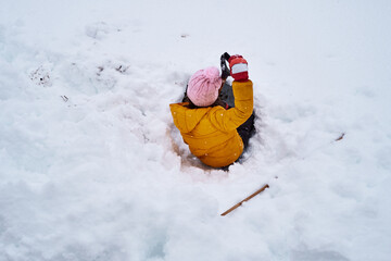 a child digs a snow cave in the garden