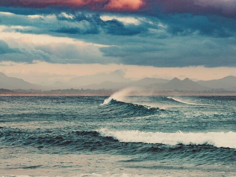 A view of Mt Warning from Byron Bay as a wave breaks