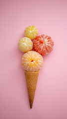 Ice cream cone with peeled citrus fruits on pink background. Minimal summer concept. Flat lay.