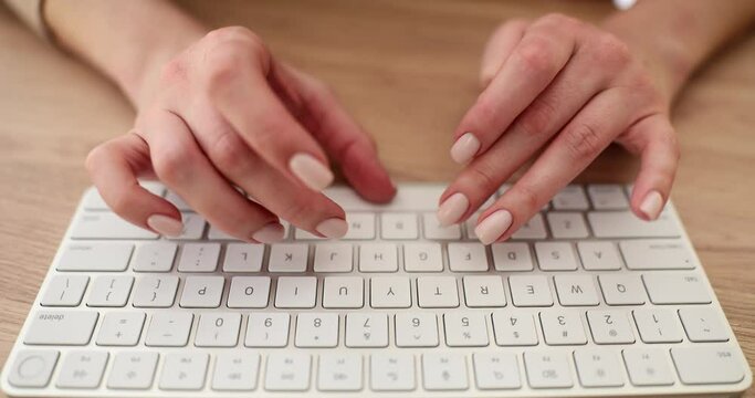 Woman types on stylish wireless keyboard at wooden table slow motion. Lady uses contemporary computer accessory in office. Digital technology