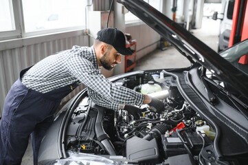 Adult man in blue colored uniform works in the automobile salon.