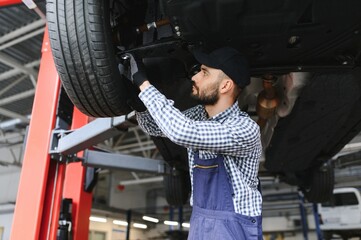 Obraz na płótnie Canvas Auto mechanic working underneath a lifted car