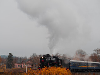 Fototapeta na wymiar Vintage soviet steam train locomotive. Karelian Express, autumn landscape