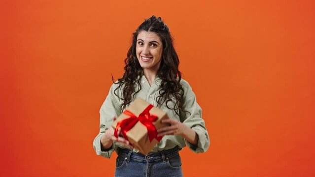Caucasian pretty woman showing you a gift box with happy surprise inside, smiling looking at camera