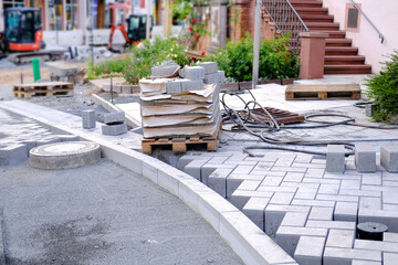 gray paving blocks on ballast, sewer well, construction site of pavement modern granite cobblestone...