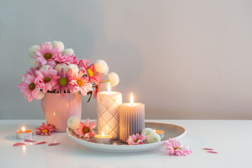 burning candles and pink and white  chrysanthemums in white interior